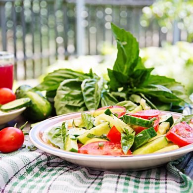 Breakfast in the summer garden. Salad of tomatoes and cucumbers with green onions and basil.