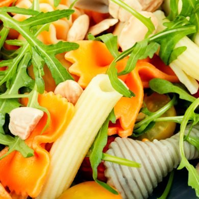 Salad with fresh tomatoes, greens and pasta on a plate. Healthy diet food. Close up.